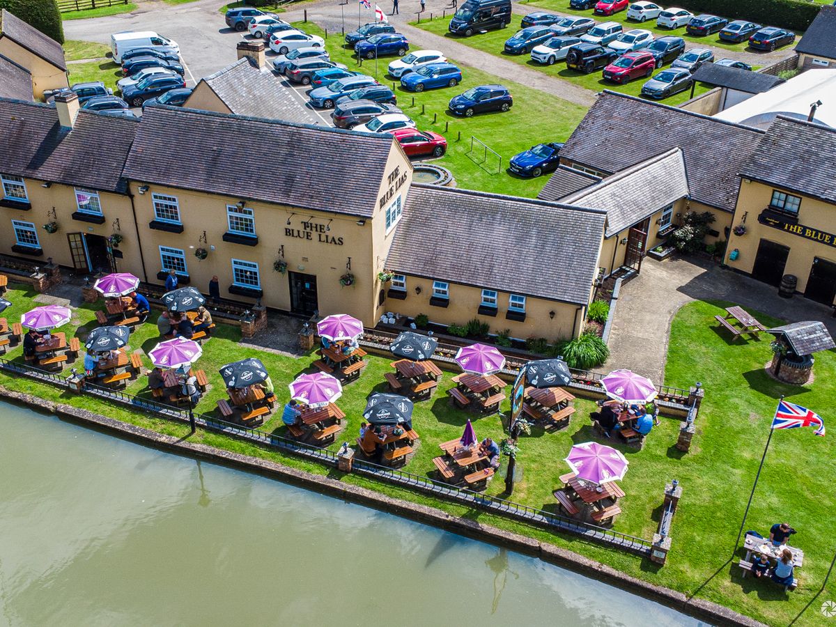 Aerial view of a canal-side pub with a busy beer garden
