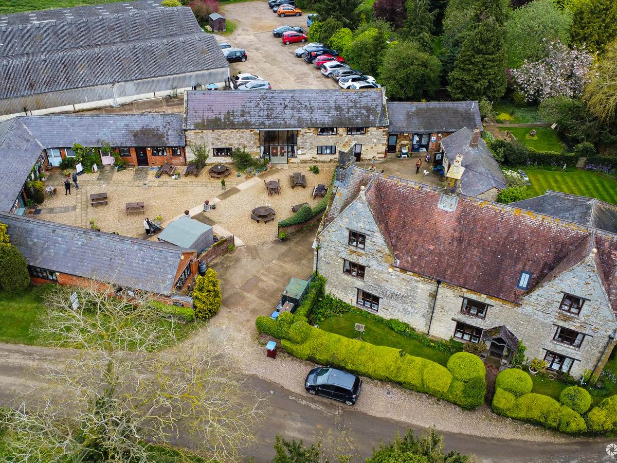 Aerial view of a stone farm courtyard and car park